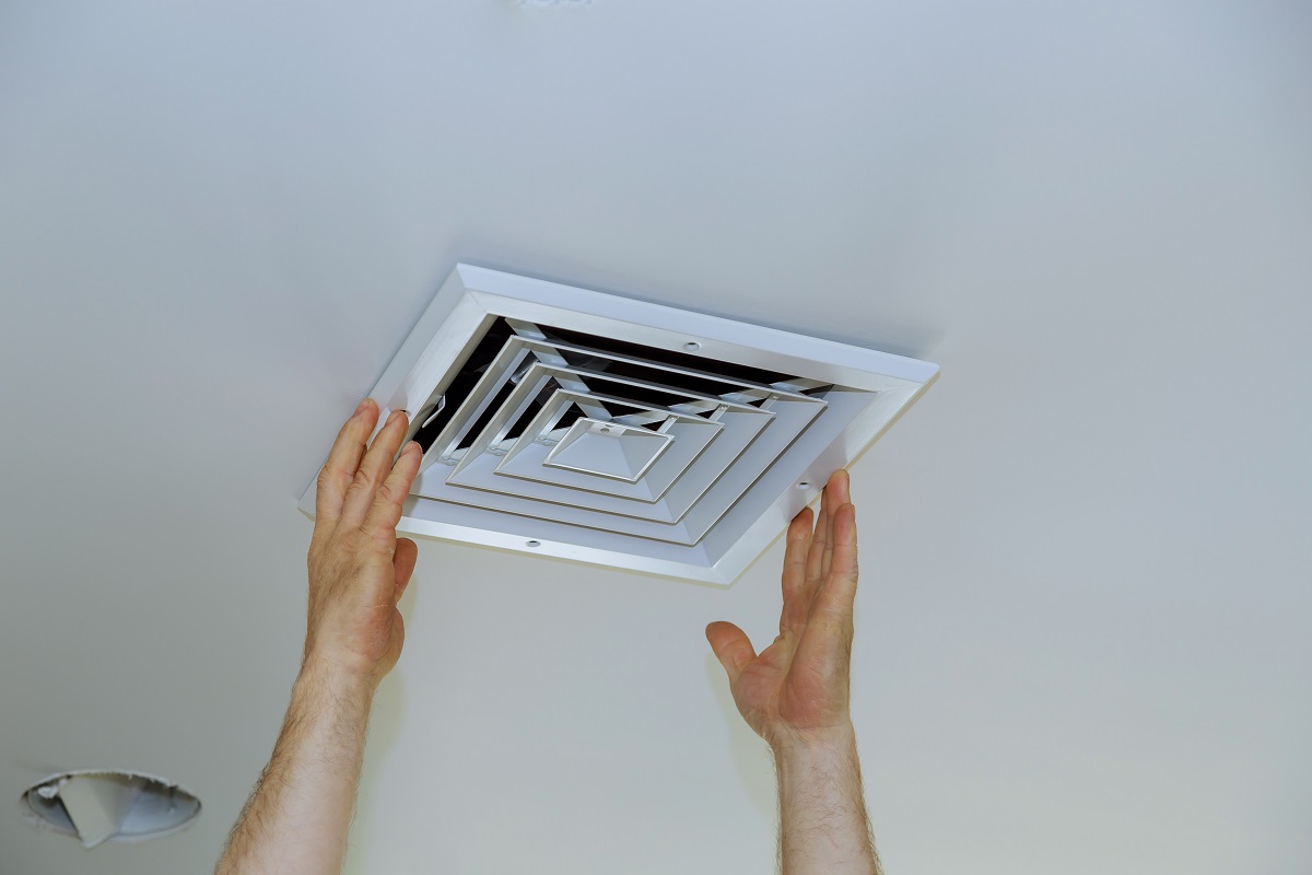 Close up man hand installing vent cover from ceiling