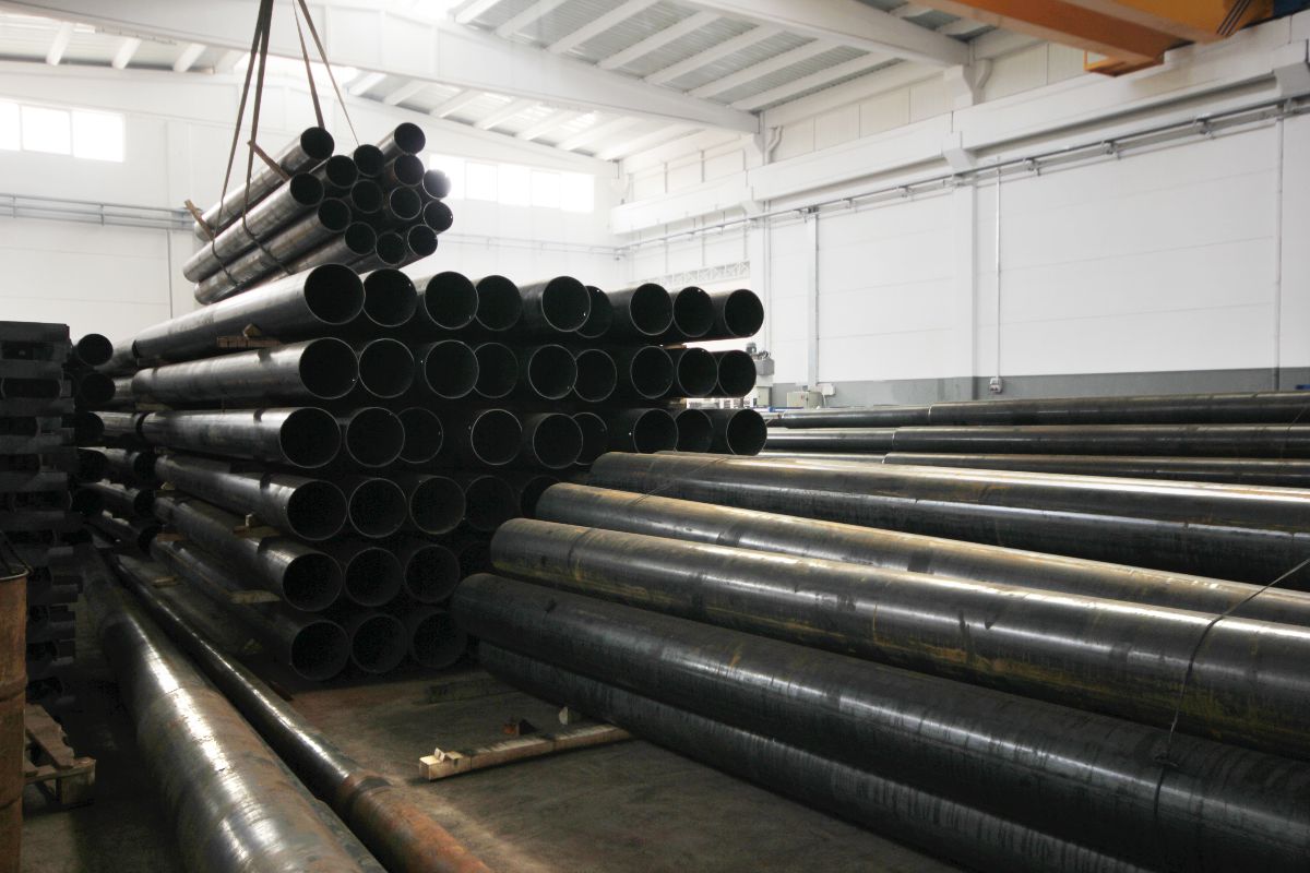 Stacked black steel pipes stored in an industrial warehouse