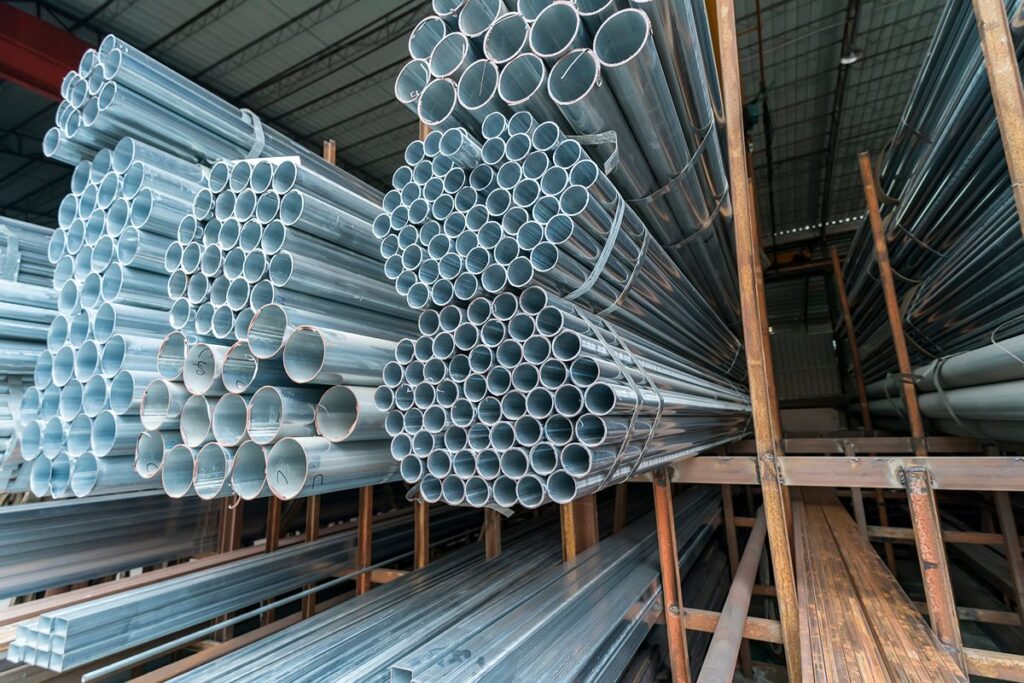 Bundles of galvanized steel pipes organized on storage racks inside a supplier’s warehouse