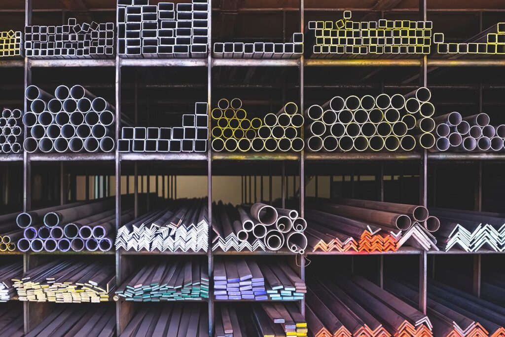 Different steel pipes, tubes, bars, and angle sections organized on warehouse shelving