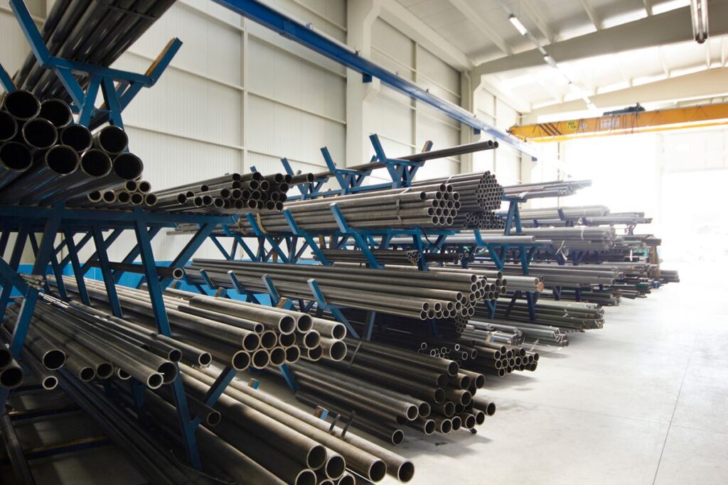 Bundles of black iron pipes stored on blue industrial racks inside a warehouse