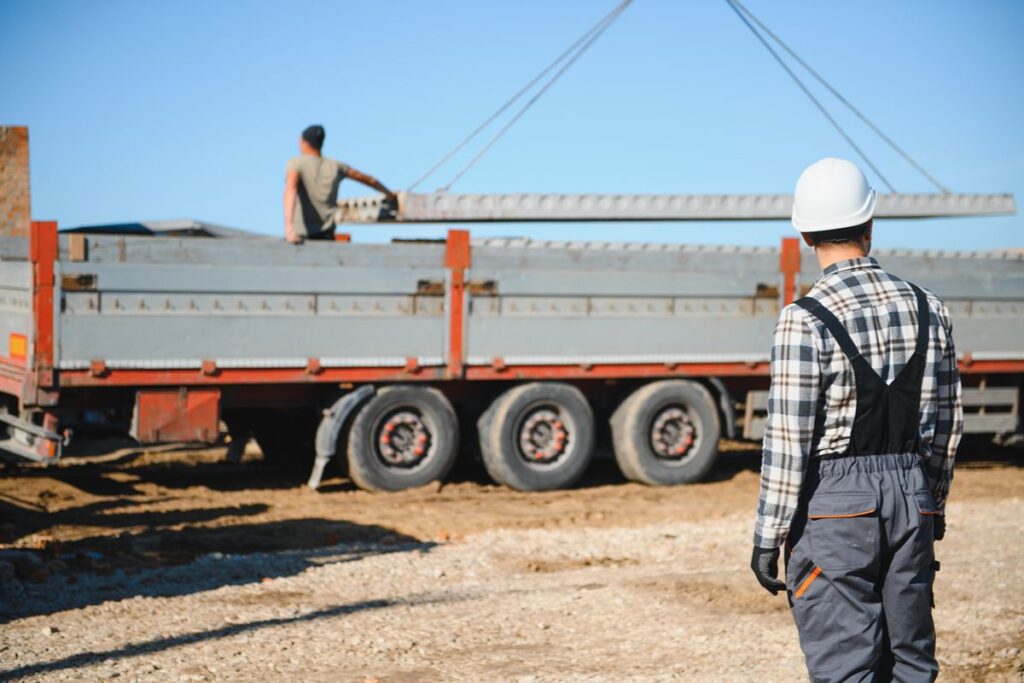 Project worker oversees steel materials being loaded onto a truck for construction site delivery.