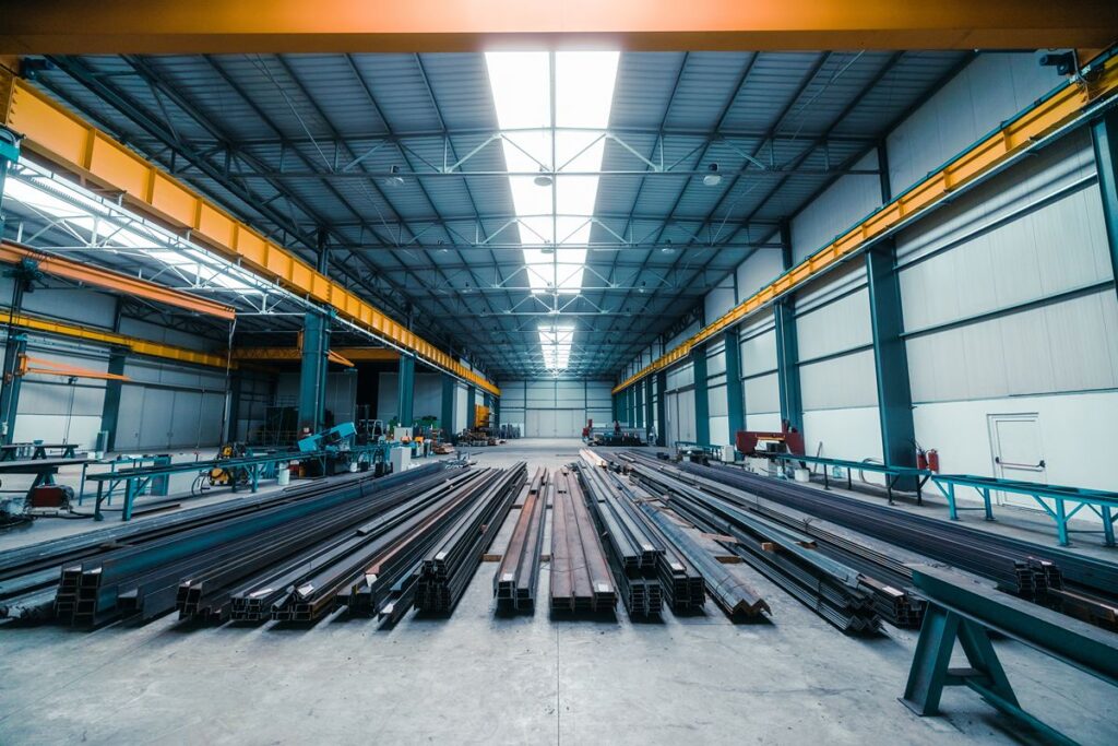 Long steel pipes arranged inside a large fabrication facility for planned project supply and distribution.