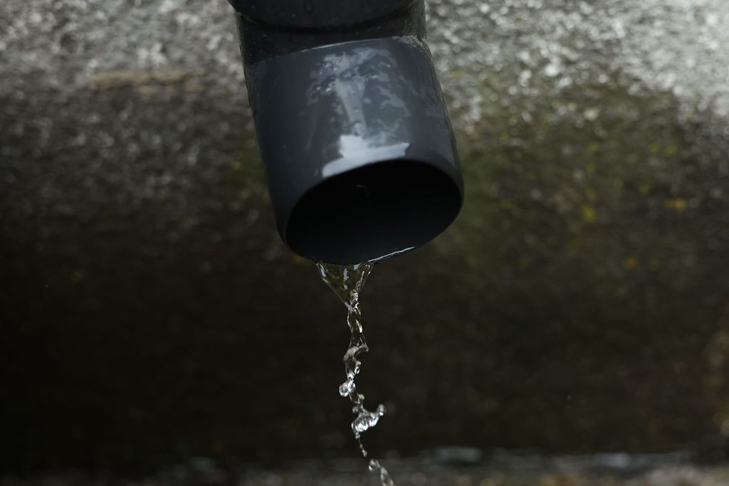 Black iron pipe carrying water, illustrating moisture exposure and corrosion considerations in water-related applications