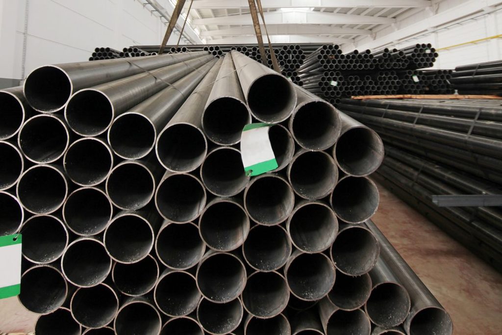 Bundles of steel pipes stored in a warehouse, representing stock availability and order requirements that affect delivery lead time