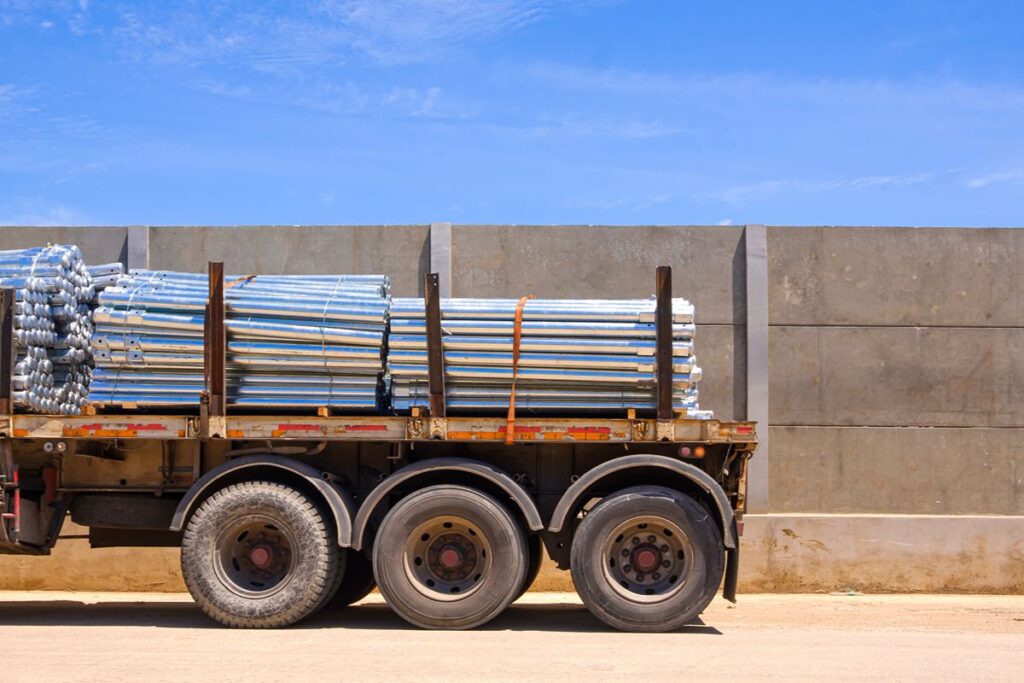 Bundled galvanized iron pipes secured on a delivery truck for transport to a construction project